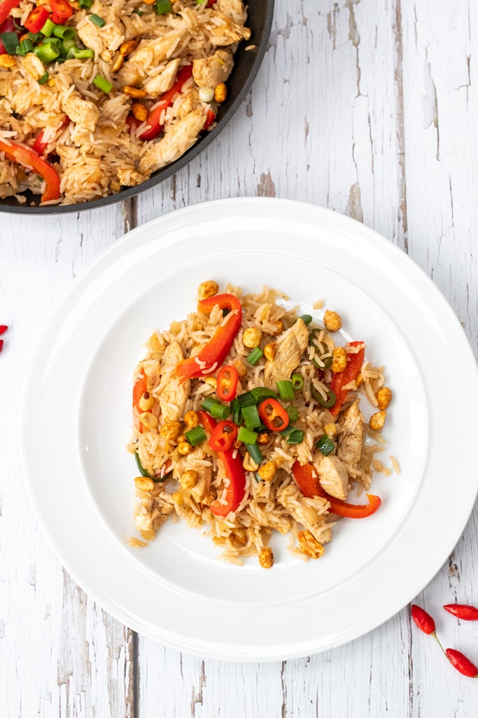 chicken fried rice on a plate with a pan in the background