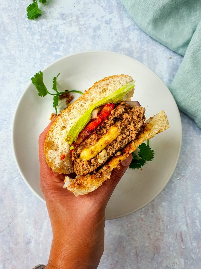 Hand holding a cheese stuffed burger 