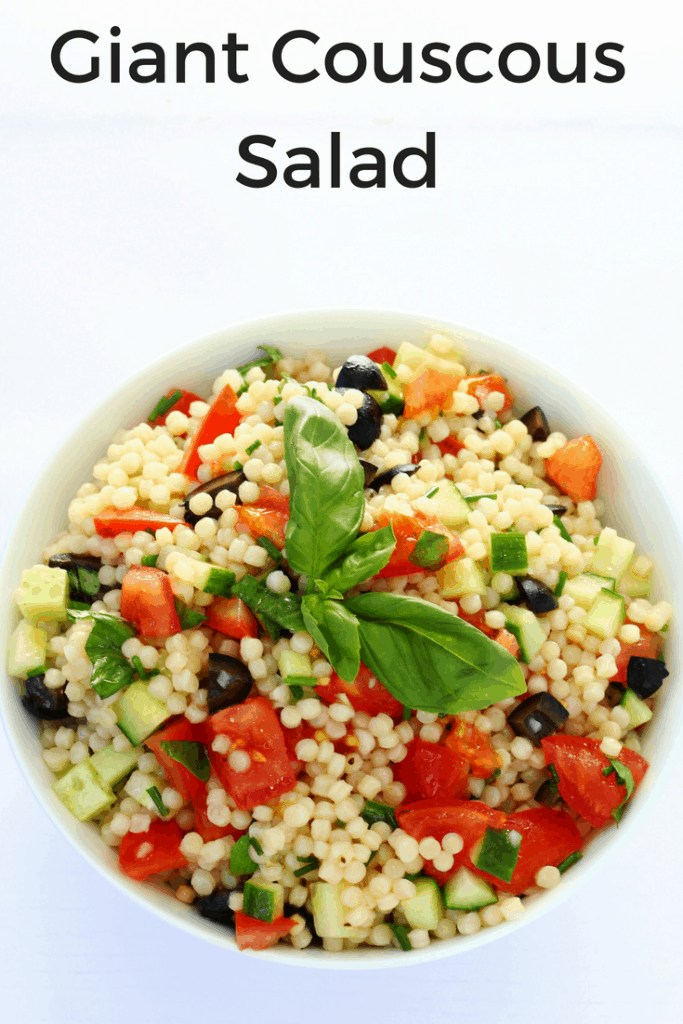 bowl of giant couscous salad topped with basil leaves