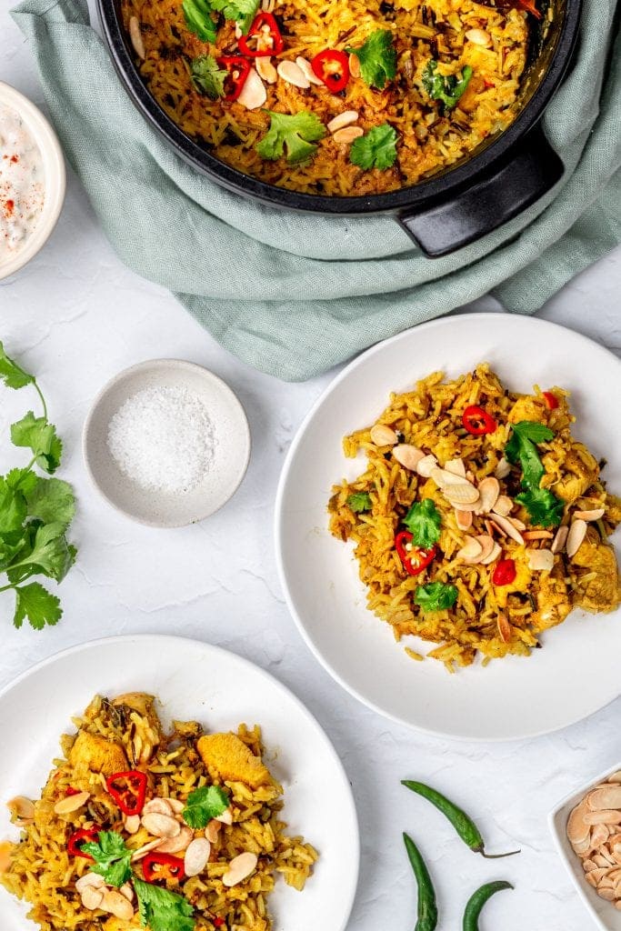 flatlay of chicken biryani with pot and plates