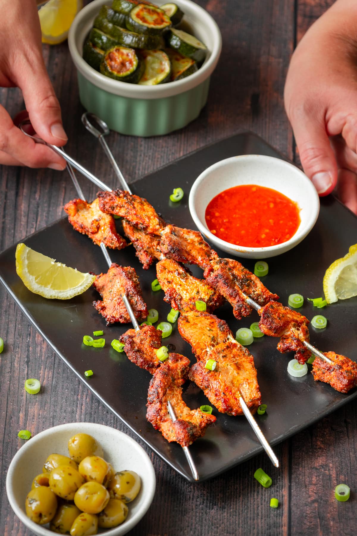 hands picking up spanish pork skewers