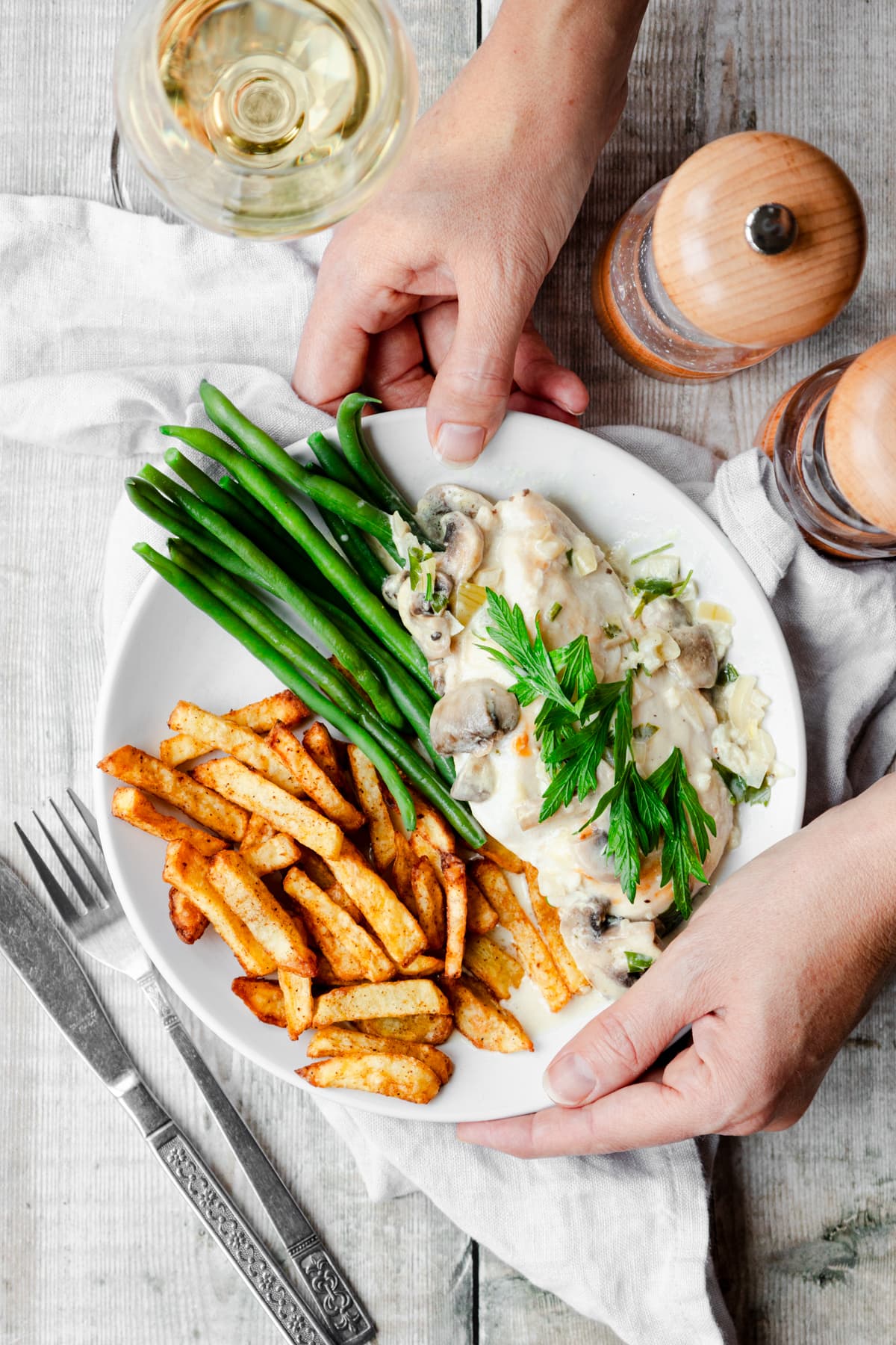 hands holding a plate of chicken in creamy mushroom sauce