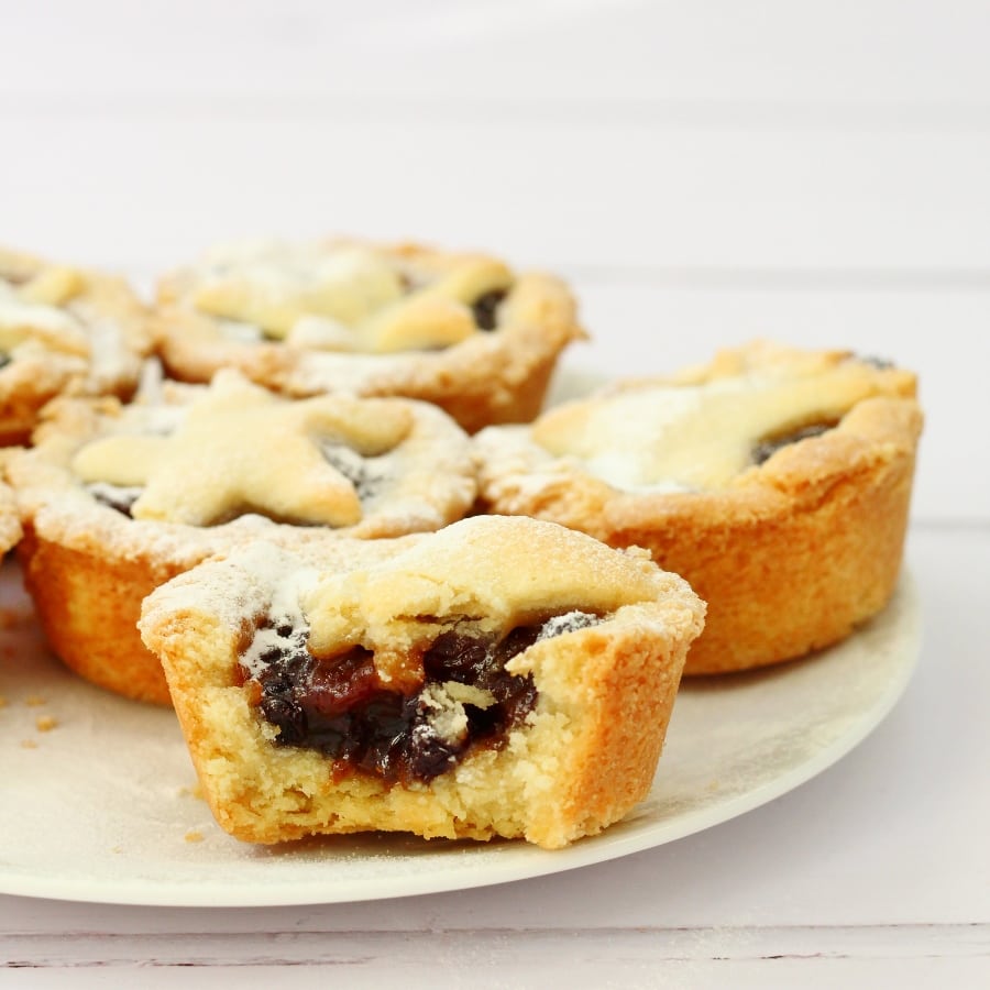 Plate of mince pies. One mince pie has a bite taken out.