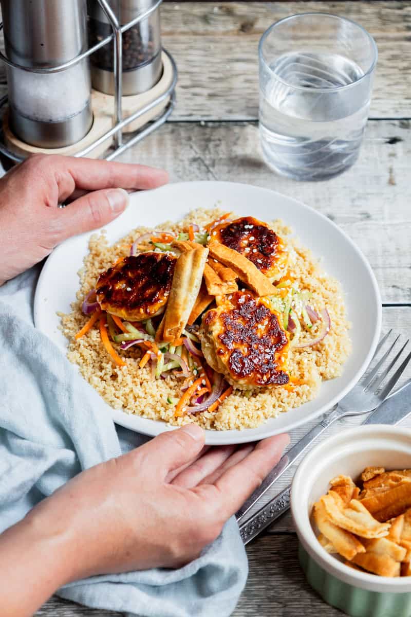 Plate of couscous topped with salad and sesame feta fritters