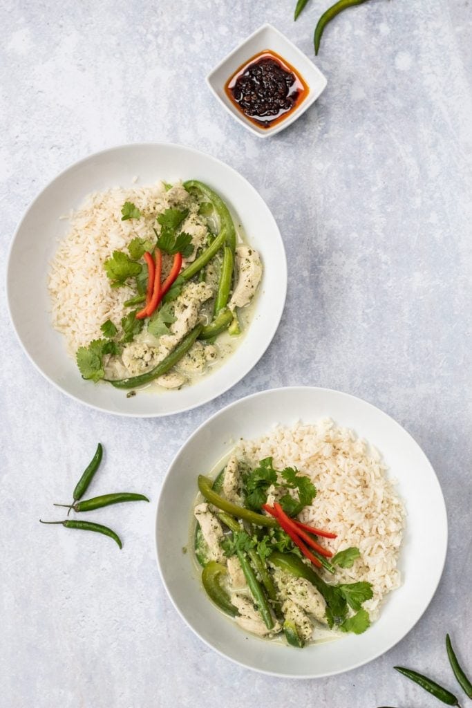 Two bowls of Thai green curry and chilli sauce