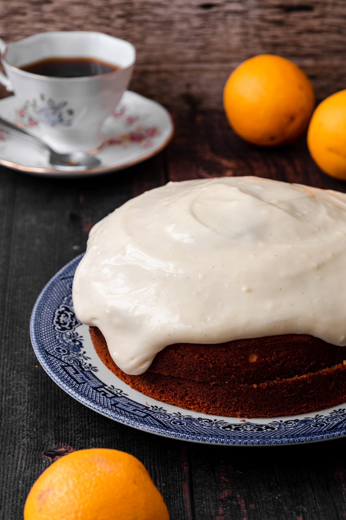 orange buttermilk cake with oranges and cup of tea in background