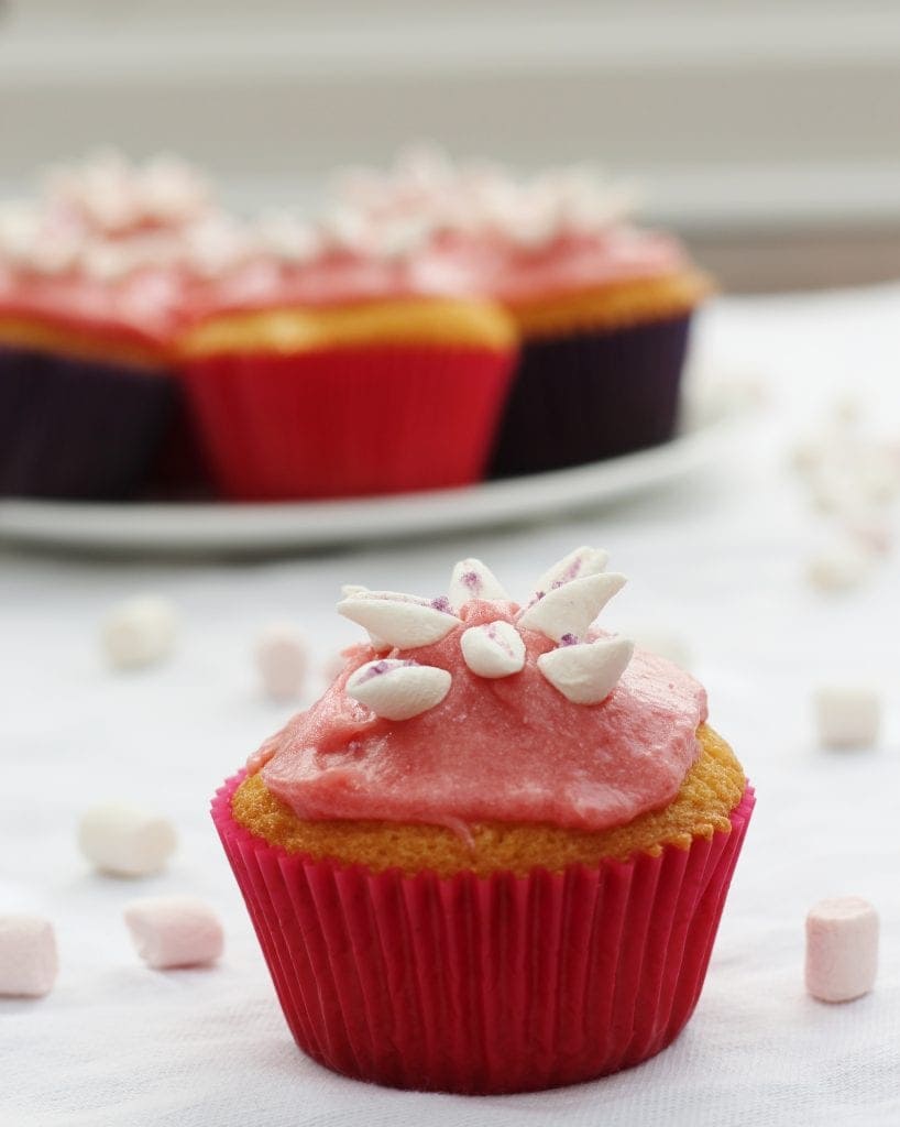 Marshmallow Flower Cupcake in foreground with plate of cupcakes in background