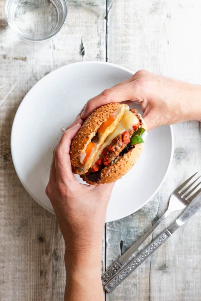 Hands holding a beef and chorizo burger