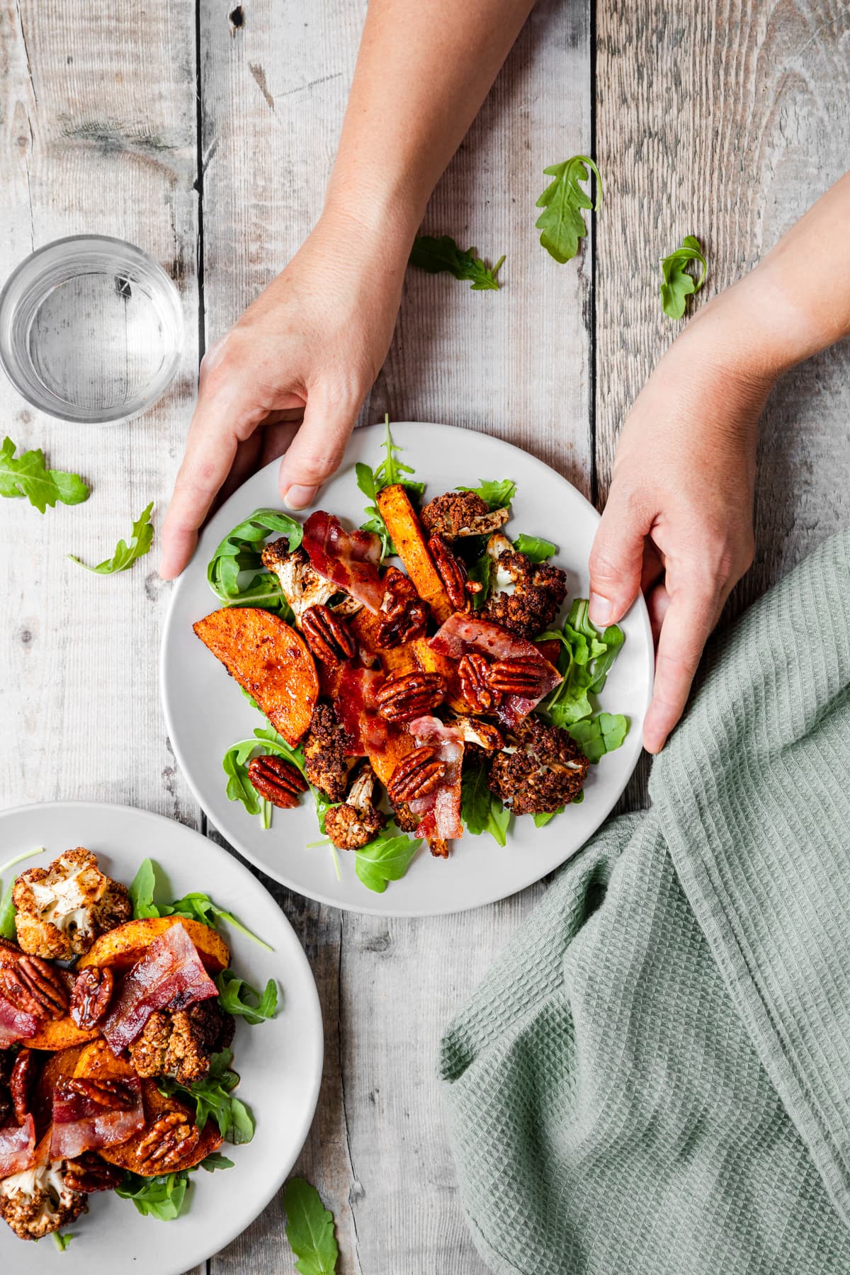 hands holding plate of butternut squash cauliflower salad