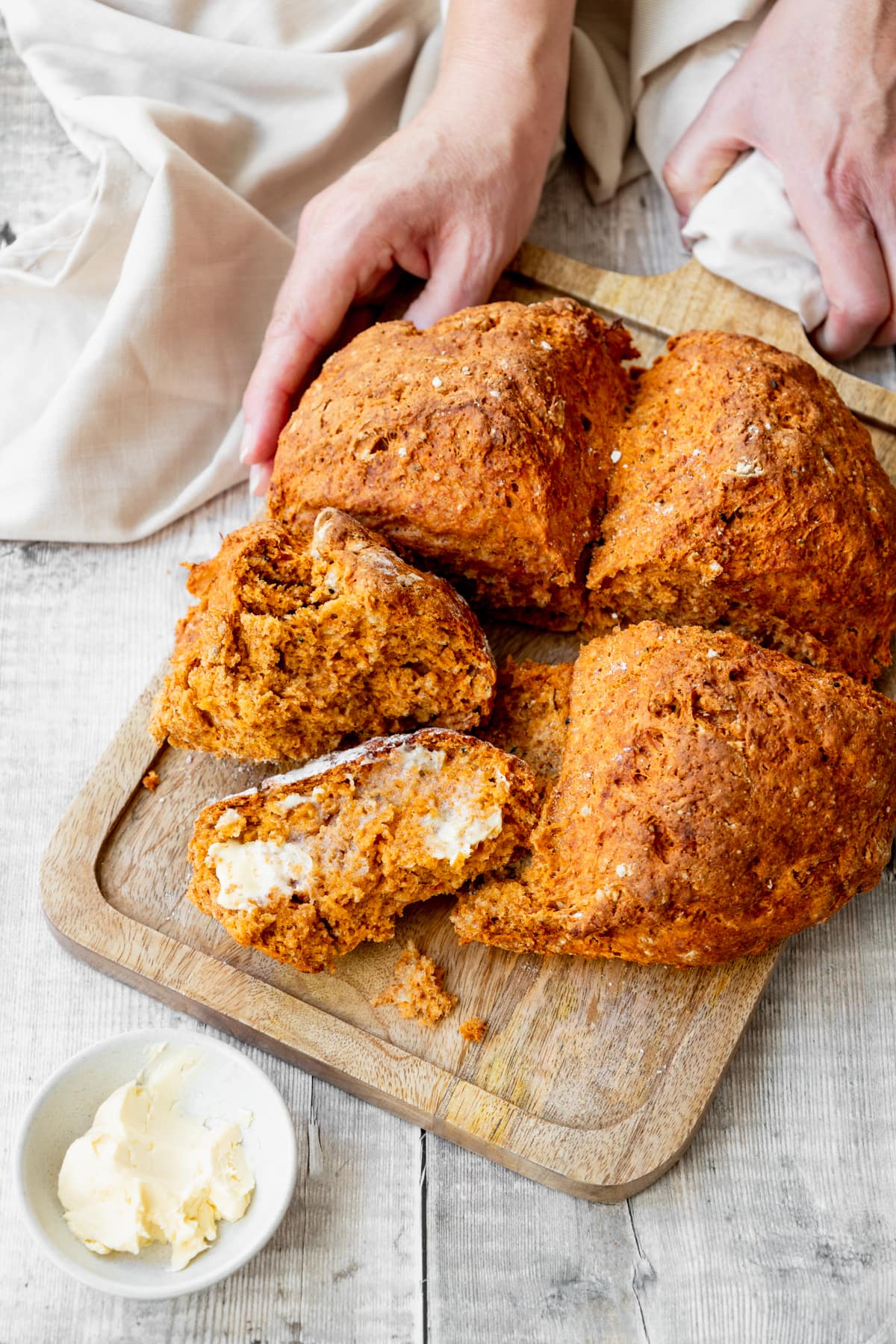 Hands holding board with tomato nigella seed quick bread