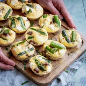 Mini frittatas on a board with asparagus and mushrooms