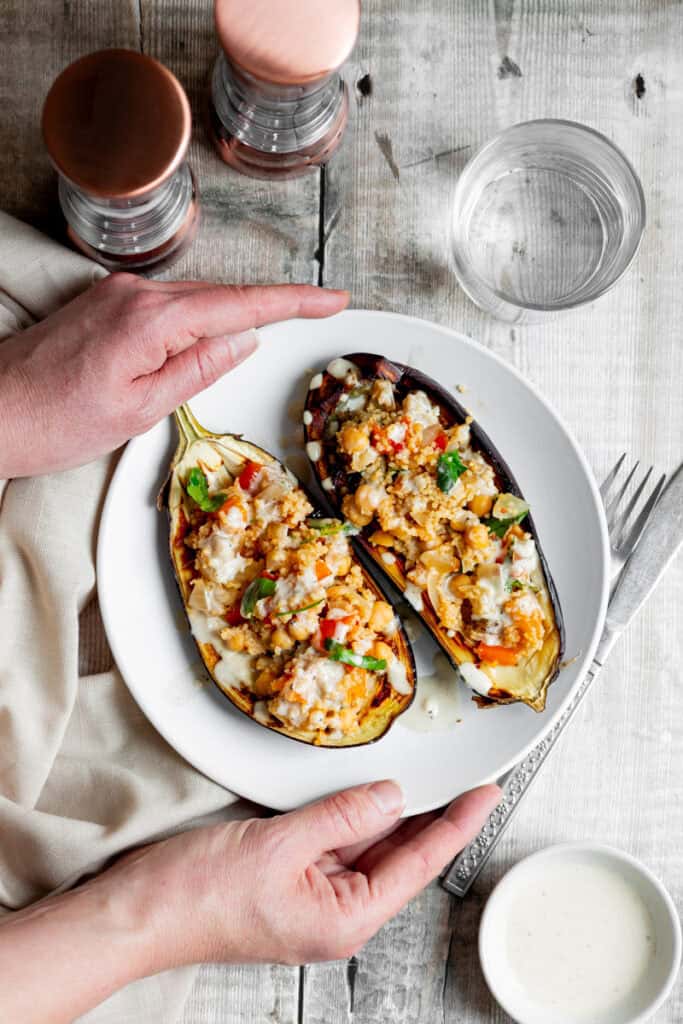 hands holding a plate of stuffed aubergine