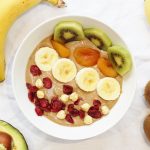 Healthy Nutella smoothie bowl with banana and avocado topped with banana, kiwi fruit, dried apricots, cranberries and hazelnuts