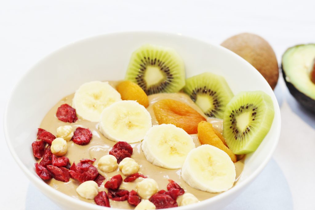 Healthy Nutella smoothie bowl with banana and avocado topped with banana, kiwi fruit, dried apricots, cranberries and hazelnuts Nutella smoothie bowl topped with fruit