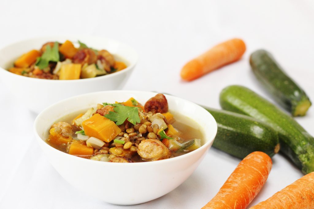 sausage lentil and vegetable soup bowls of sausage lentil vegetable soup with carrots and courgettes in the background