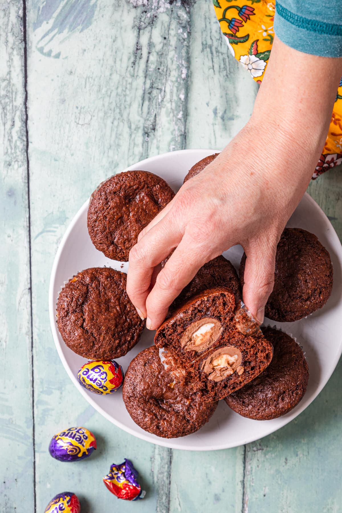 Hand taking a muffin from a plate