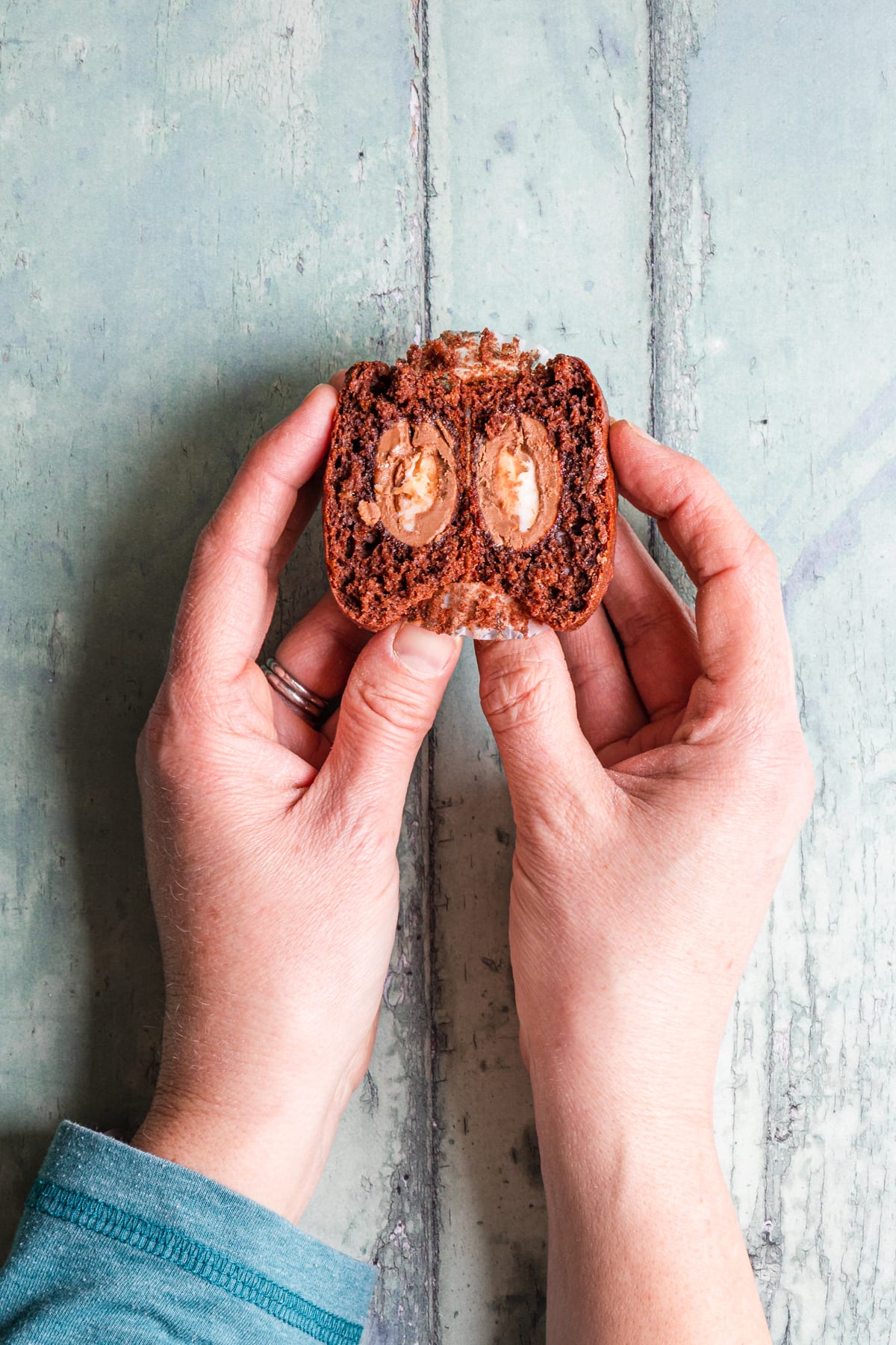 hands holding a creme egg filled muffin cut in half