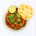 vegan lentil chilli in a bowl with a flatbread