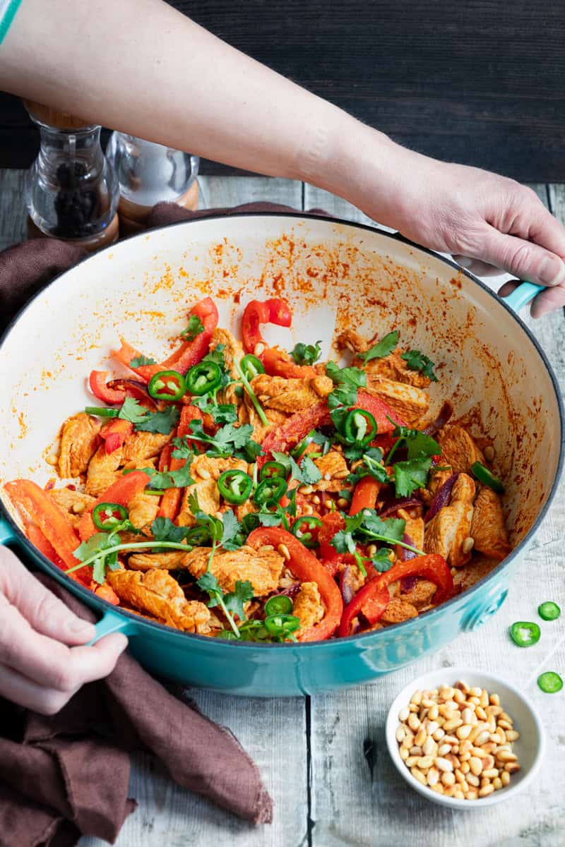 Hands holding a pan of fragrant North African chicken
