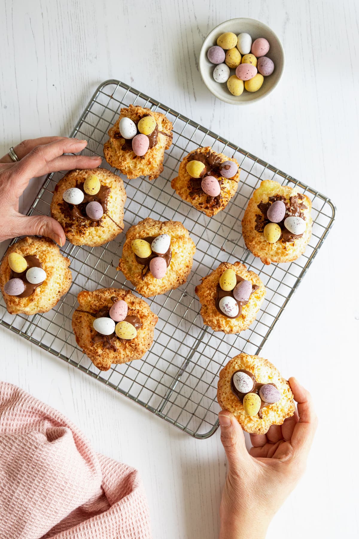 Hands taking coconut macaroons from cooling tray