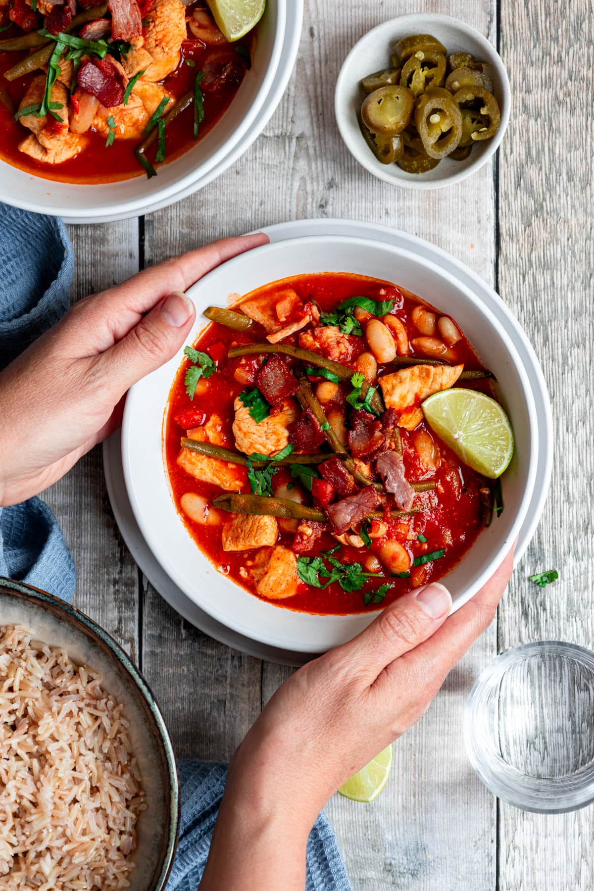 hands holding bowl of chicken and bacon chilli