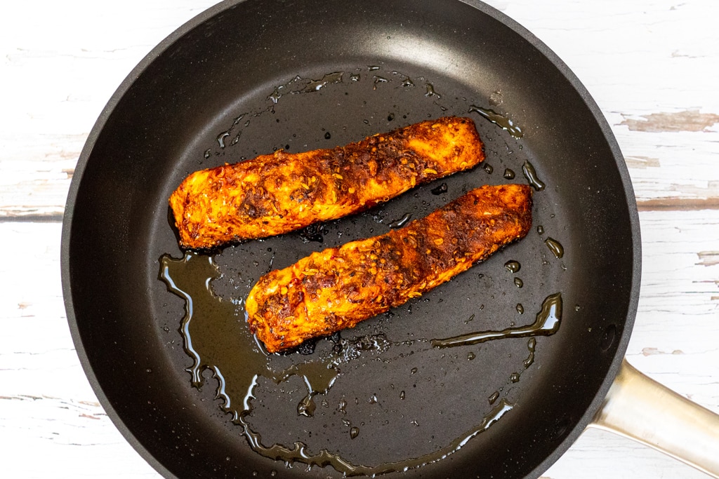 salmon in a frying pan coated in ras el hanout spice blend