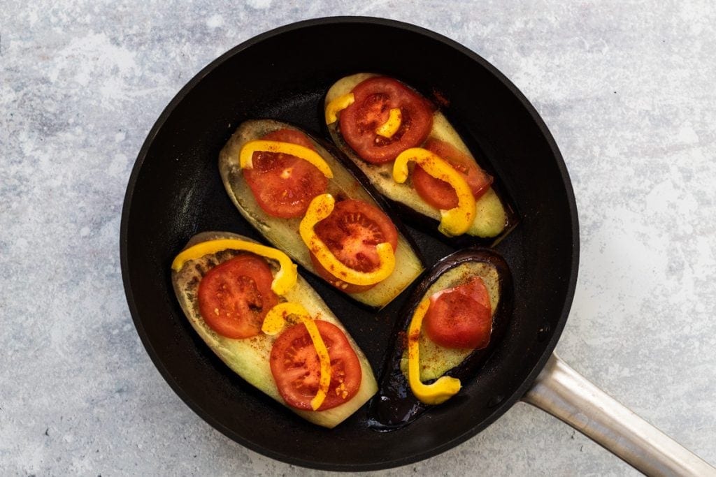 aubergine slices, tomatoes and peppers in a frying pan