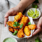 hands holding bowl of fish pakoras