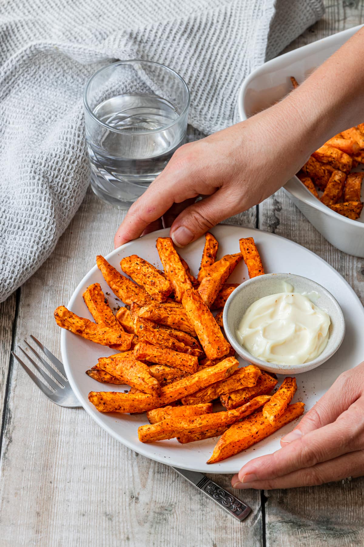 hands holding plate of Cajun air fried sweet potato fries