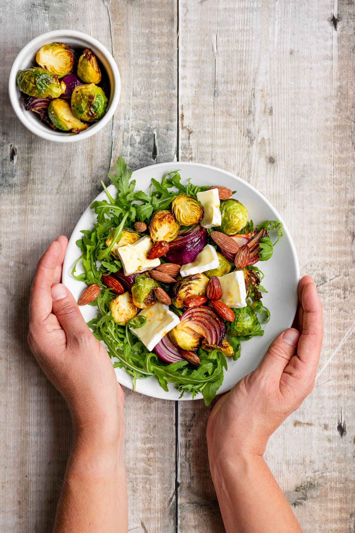 hands holding air fried brussels sprouts salad