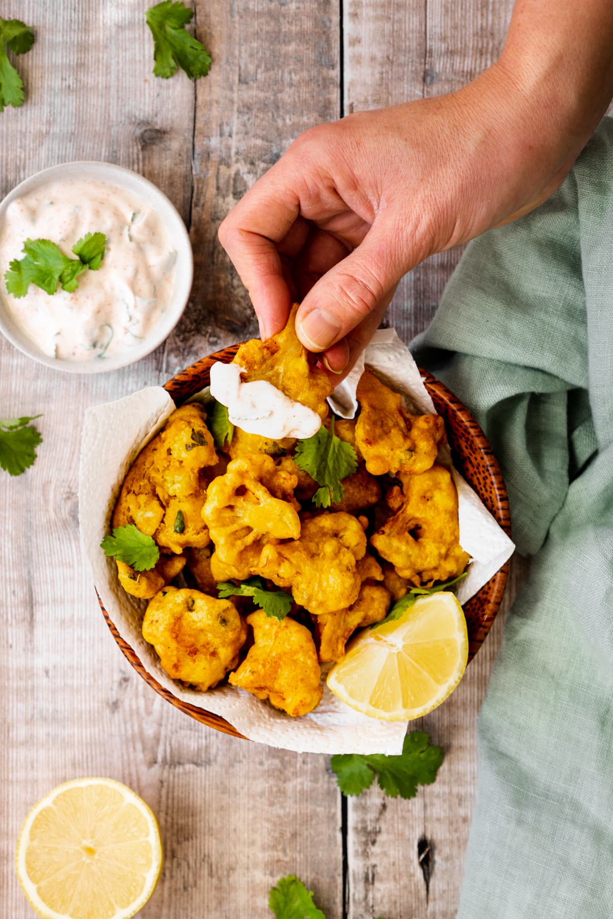 Hand taking cauliflower pakora from a bowl