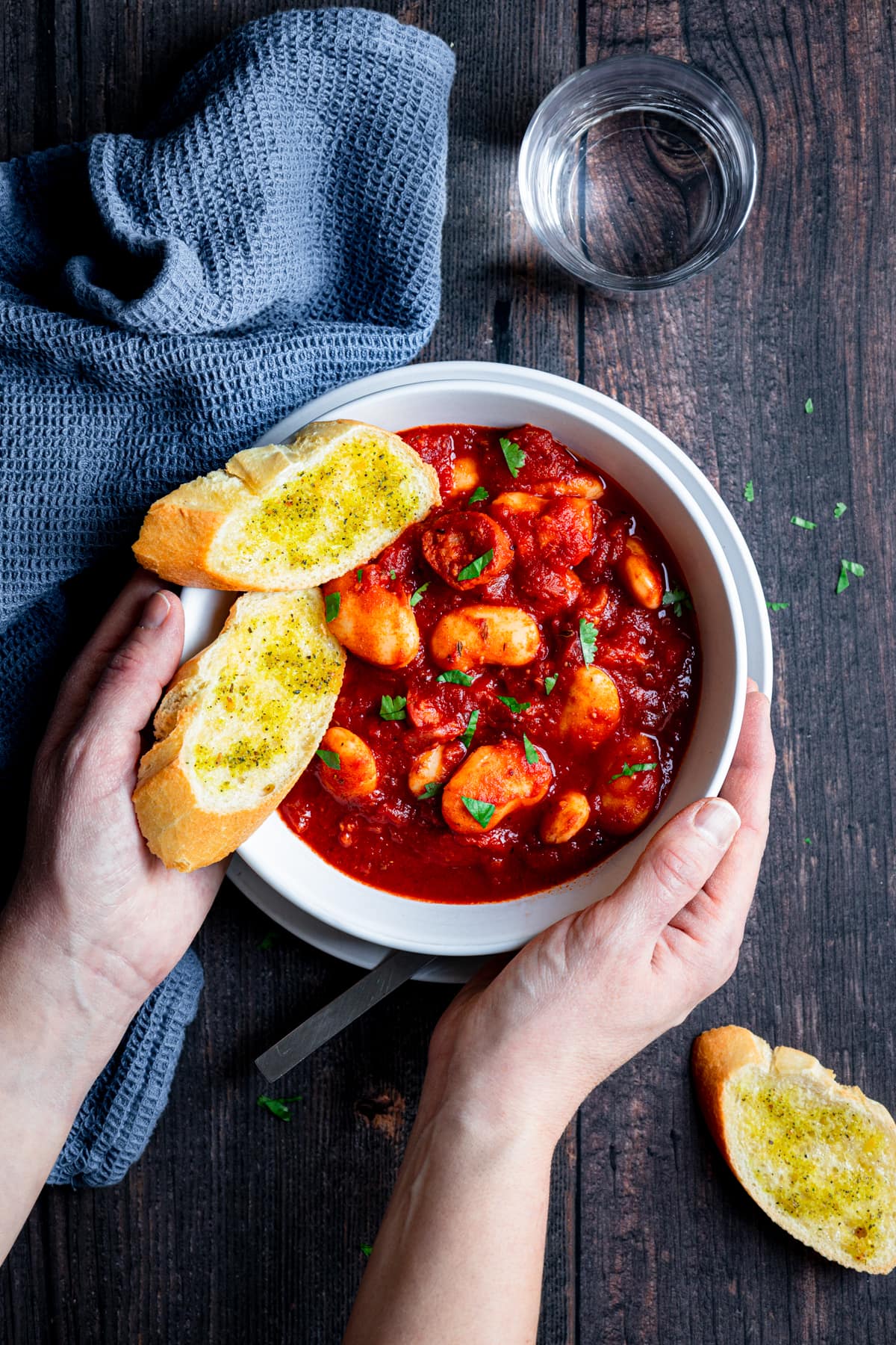 Hands holding bowl of chorizo butter bean stew