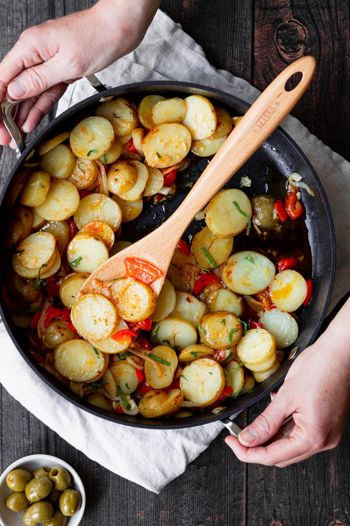 Hands holding pan of spanish saute potatoes
