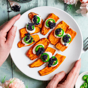 Plate of sweet potato canapes topped with sour cream, chilli pepper and caviar