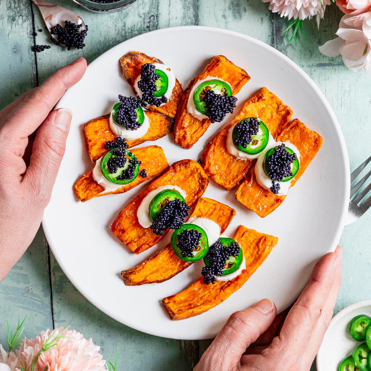 Plate of sweet potato canapes topped with sour cream, chilli pepper and caviar