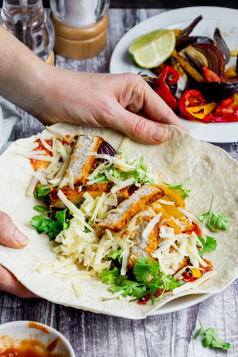 Hands holding a plate of Mexican pork wrap