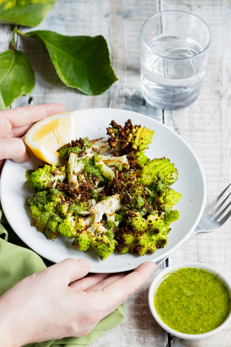 Hands putting down a plate of air fried romanesco