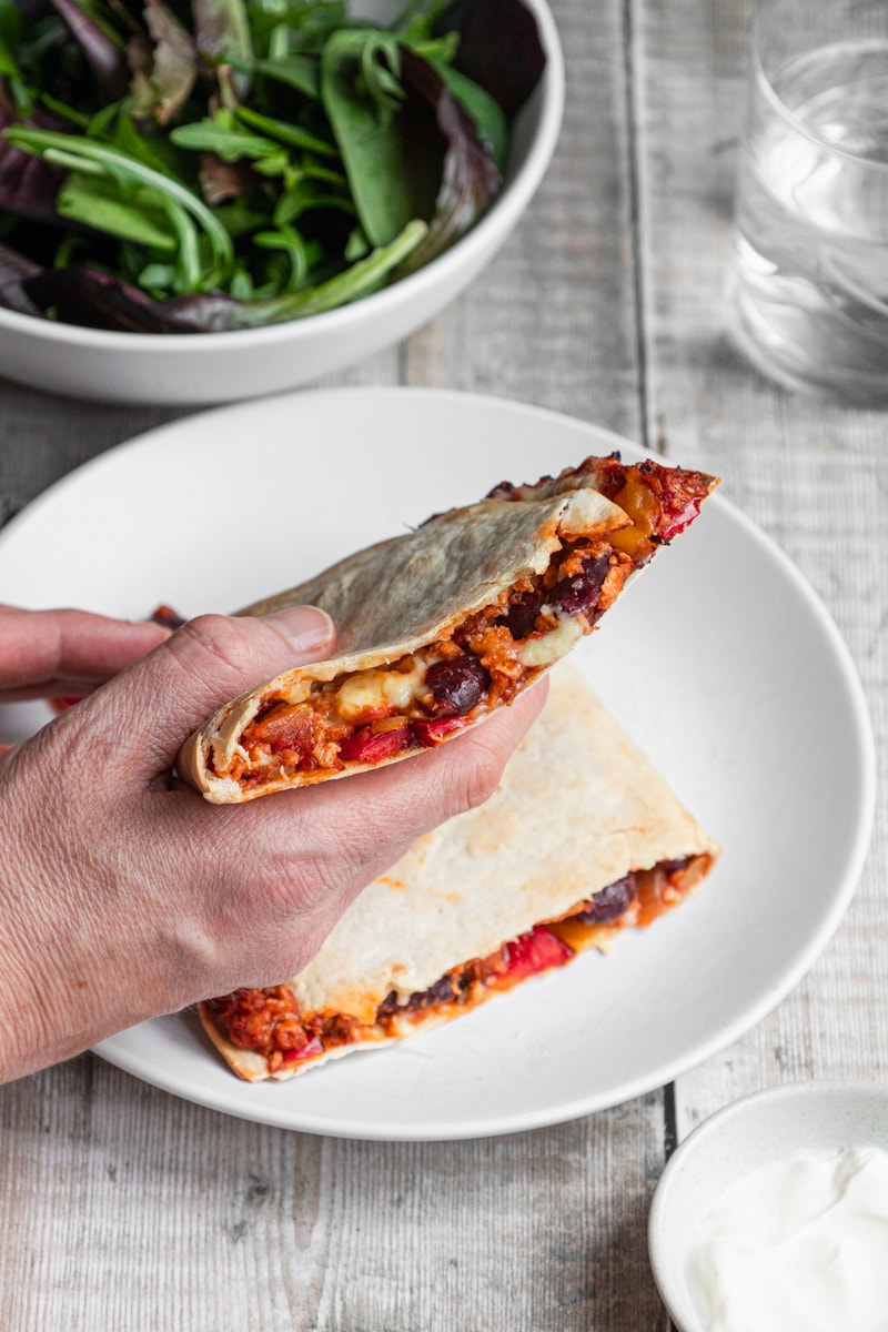Hands holding air fryer chilli con carne quesadillas
