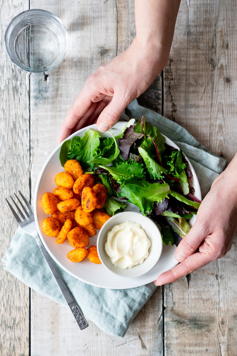 hands holding plate of air fried crispy gnocchi