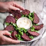 Hands holding plate of air fried beetroot