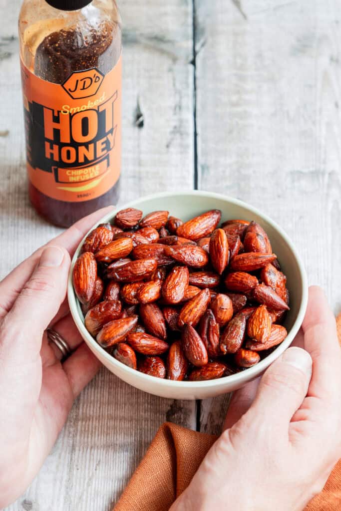 Hands holding a bowl of hot honey almonds