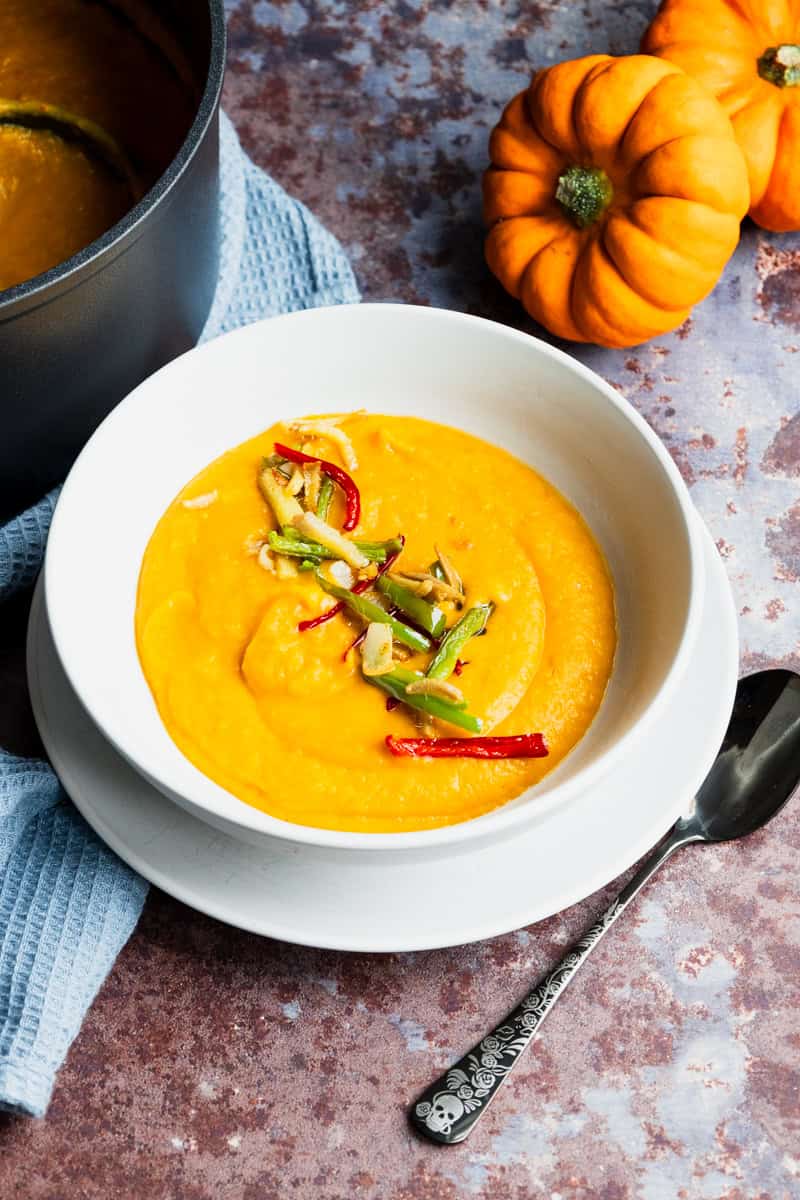 pumpkin and ginger soup with mini pumpkins in the background