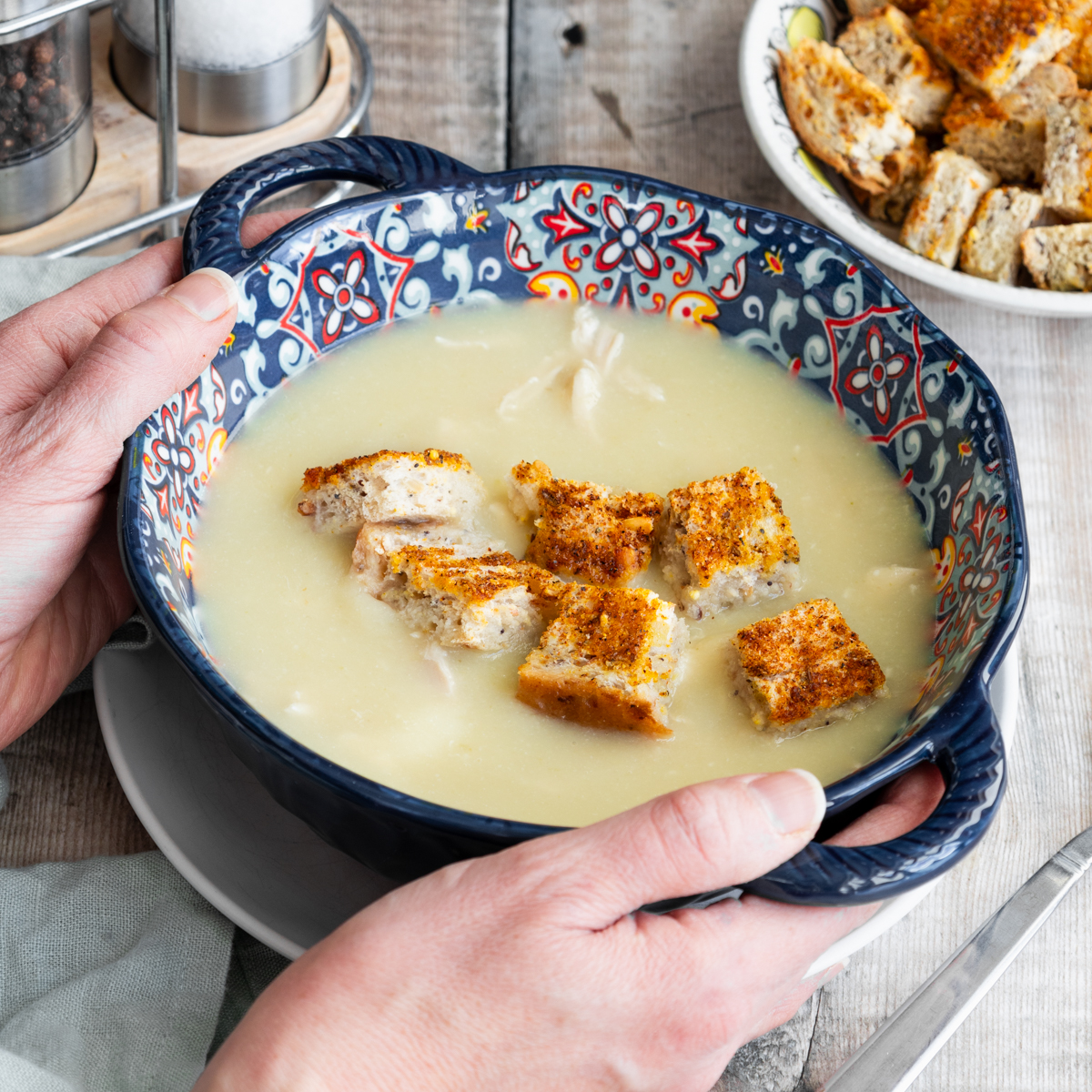 Bowl of chicken and ginger soup with hands