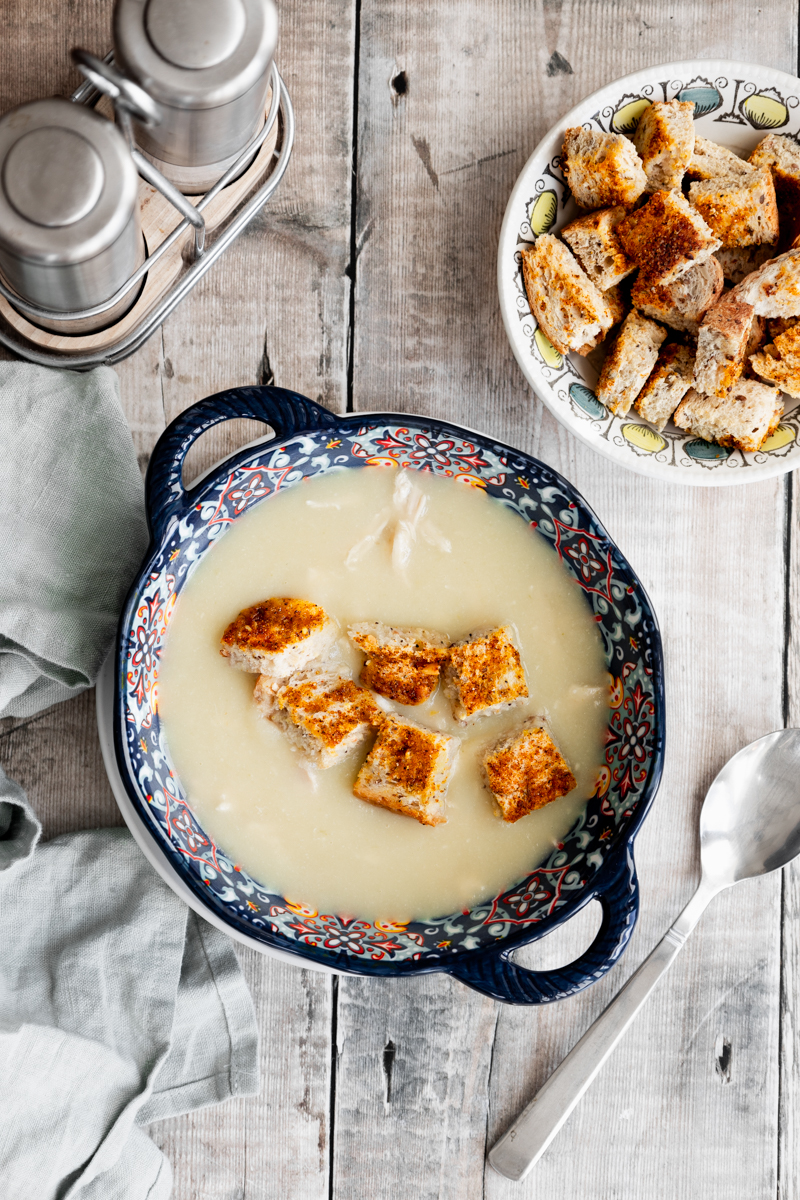 Bowl of chicken and ginger soup topped with croutons